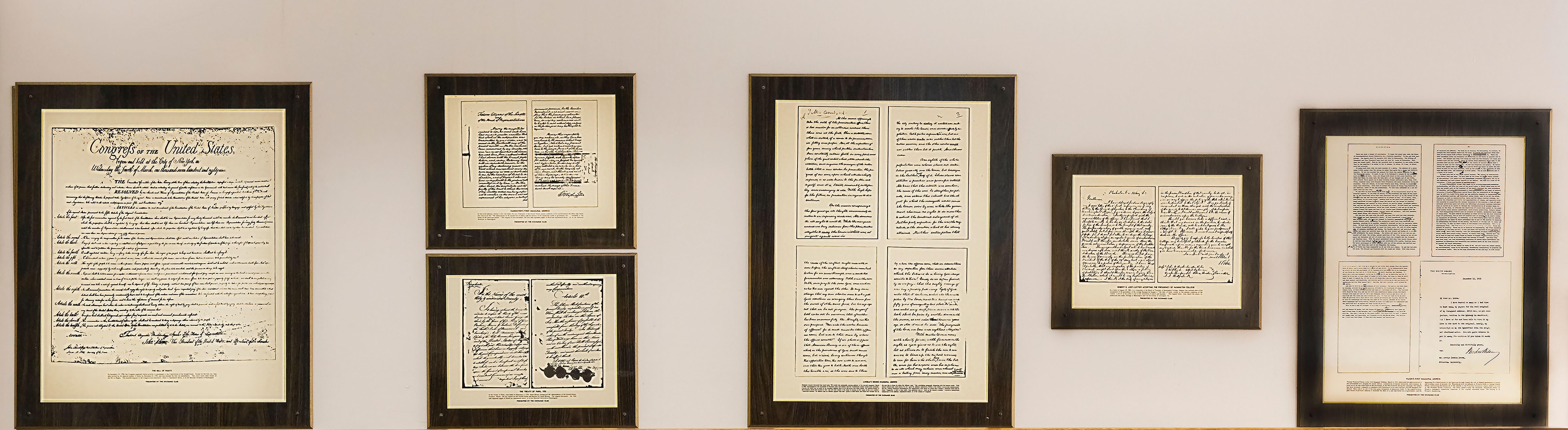 Framed reproductions of historical documents arranged along a light wall in dark frames.