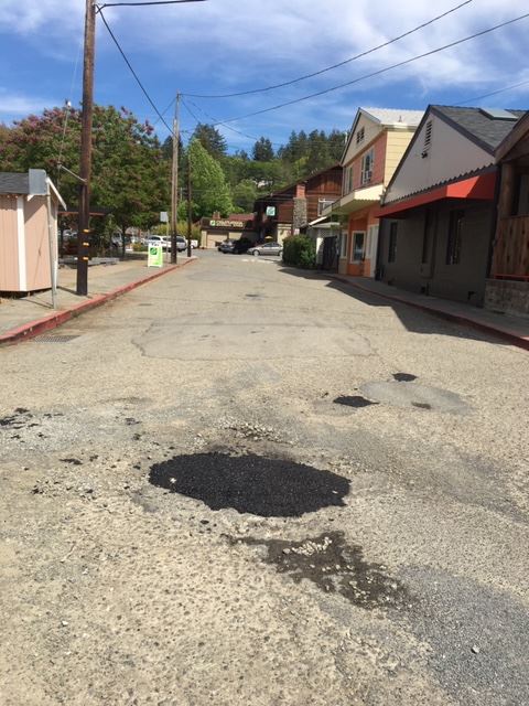 a paved road showing a recently patched pothole
