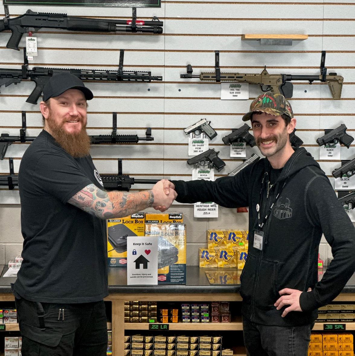 Oliver Anderson and Jonathan Abidari shaking hands at a retail firearms display